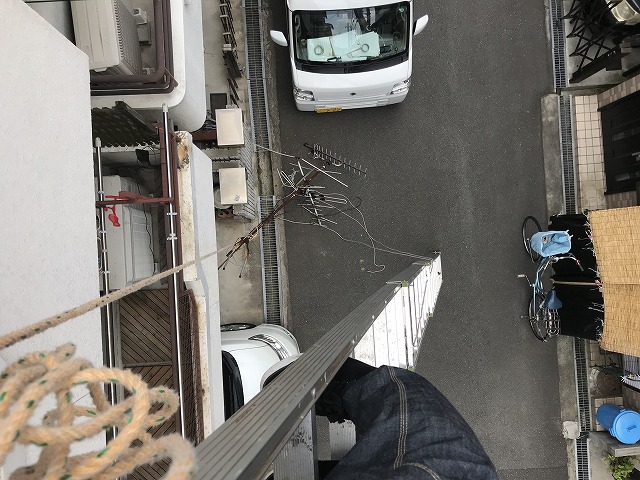 はしごで屋根のアンテナを撤去中